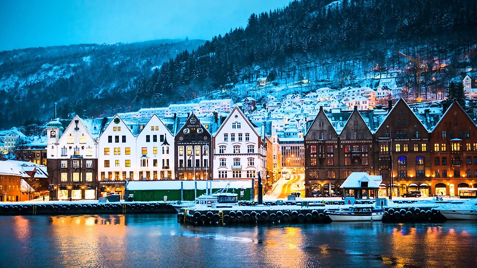 Панорамна снимка на Бриген (Bryggen) в Берген, показваща цветните дървени къщи на фона на планината и водата.