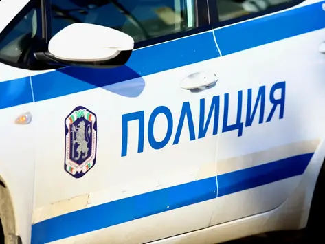 Бял български полицейски автомобил с надпис "ПОЛИЦИЯ" и емблема на Национална служба "Полиция".