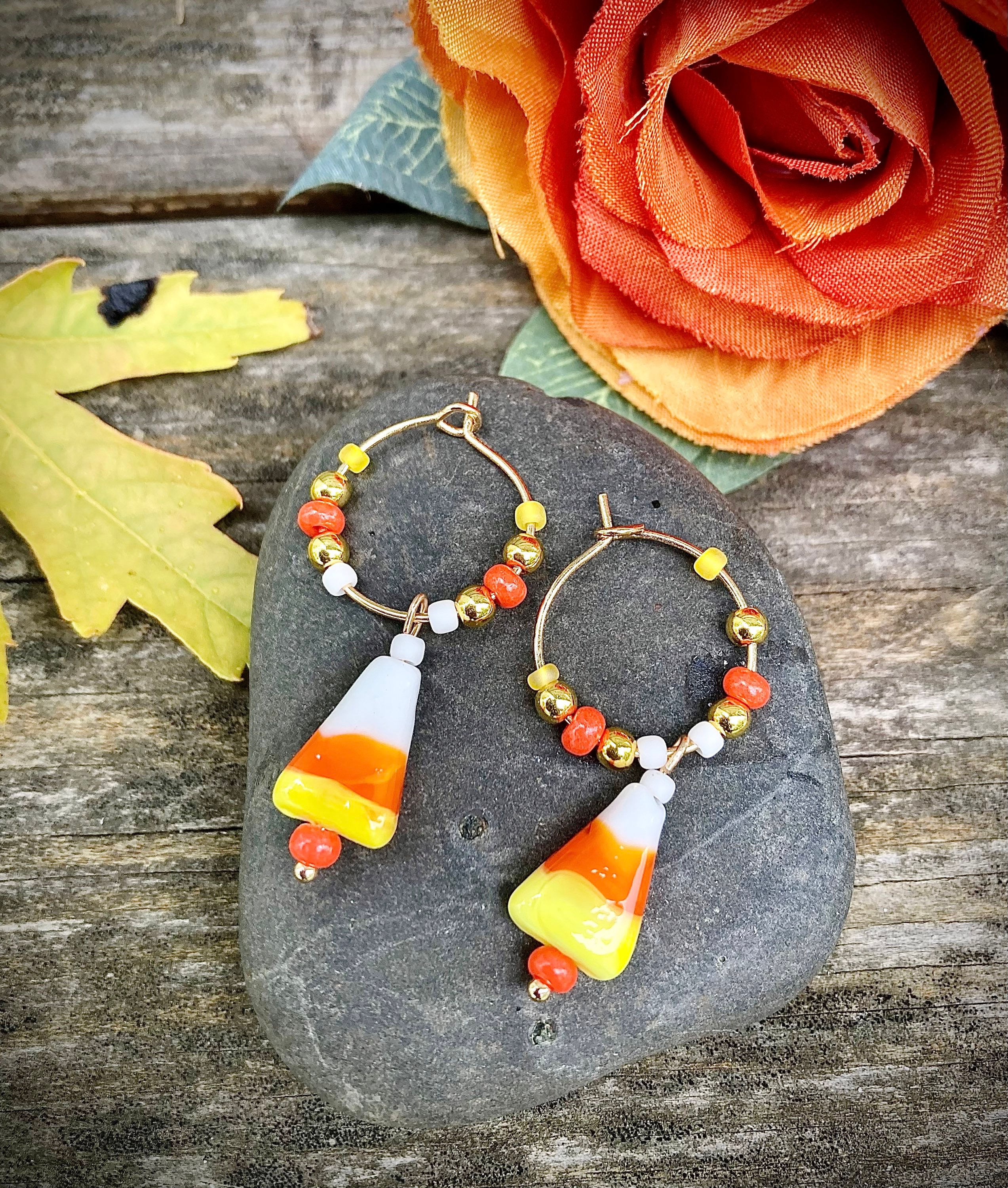 Beaded orange, yellow, white hoop earrings with glass candy corn charms.