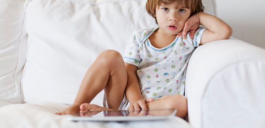 enfant boudant sur le canapé avec tablette