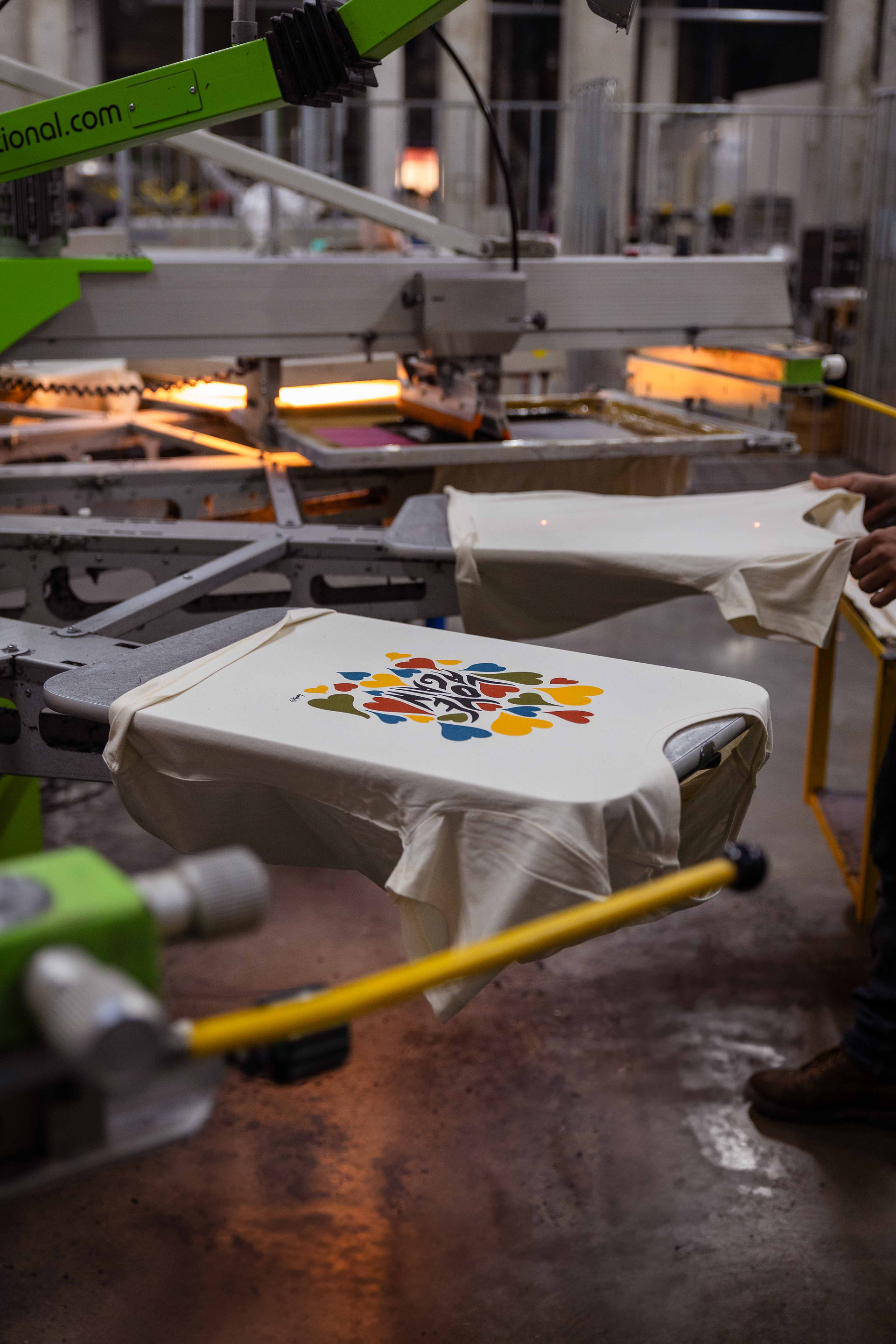 Photo de l'atelier de Normandie de l'agence Offset et d'une machine de sérigraphie en trrain d'imprimé les T-shirts de la collection de textile personnalisé pour La Maison Tellier