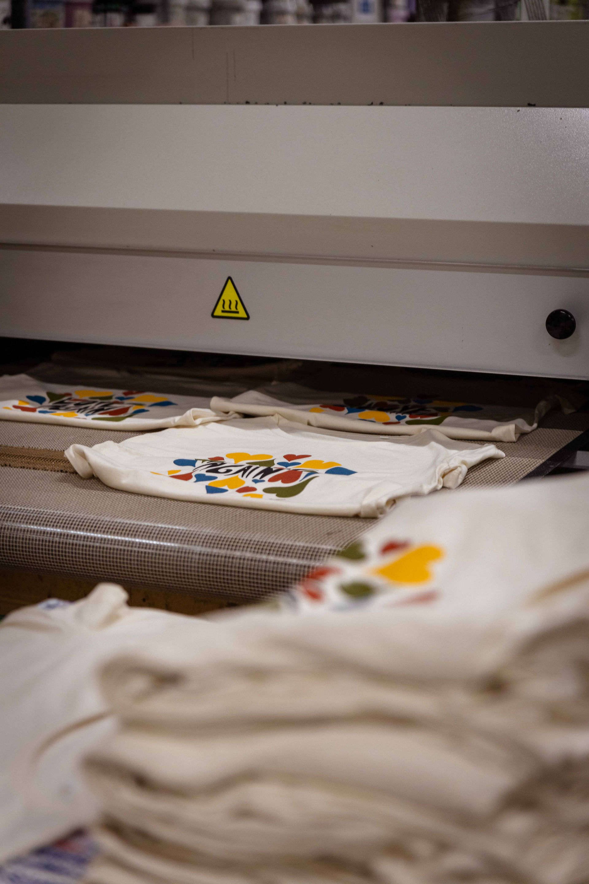 Photo de l'atelier de Normandie de l'agence Offset et d'une machine de sérigraphie en trrain d'imprimé les T-shirts de la collection de textile personnalisé pour La Maison Tellier