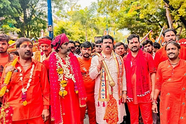 A formal group of men dressed in vibrant red outfits, accompanied by a single man wearing a red shirt.