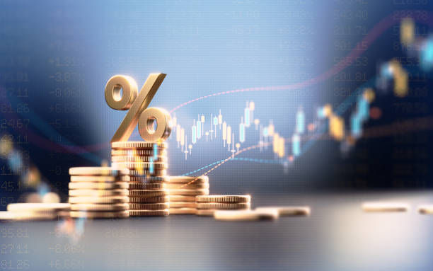 Símbolo de percentagem sobre pilhas de moedas com gráfico financeiro de rendimento ao fundo