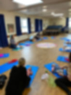 tracy demonstrating baby foot massage with mums and babies on mats in a hall