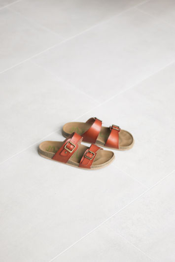 a pair of brown leather sandals on white flooring