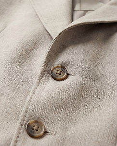 Close-up of light beige fabric garment with two brown textured buttons.