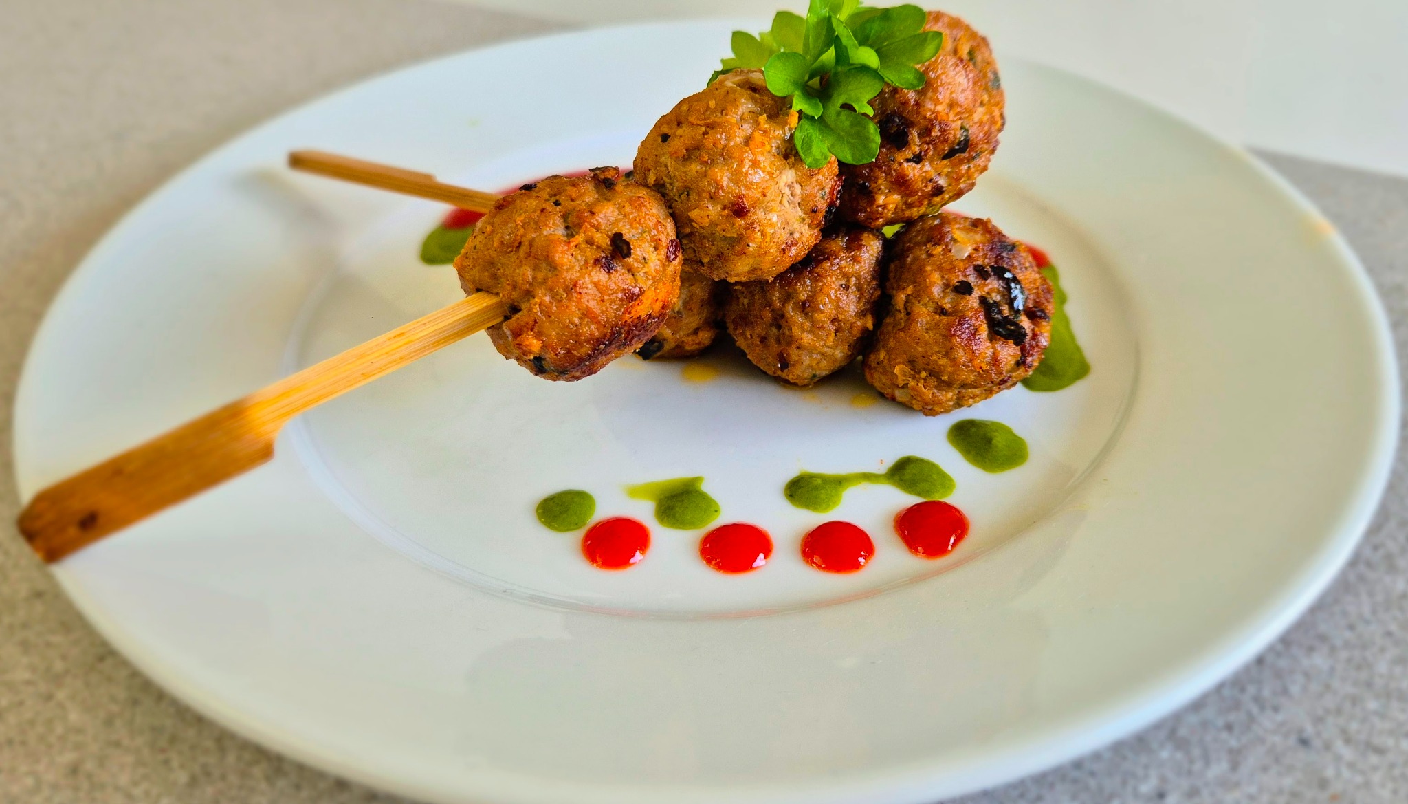Lamb kofta skewers plated with fresh garnish by Noba Kitchen.