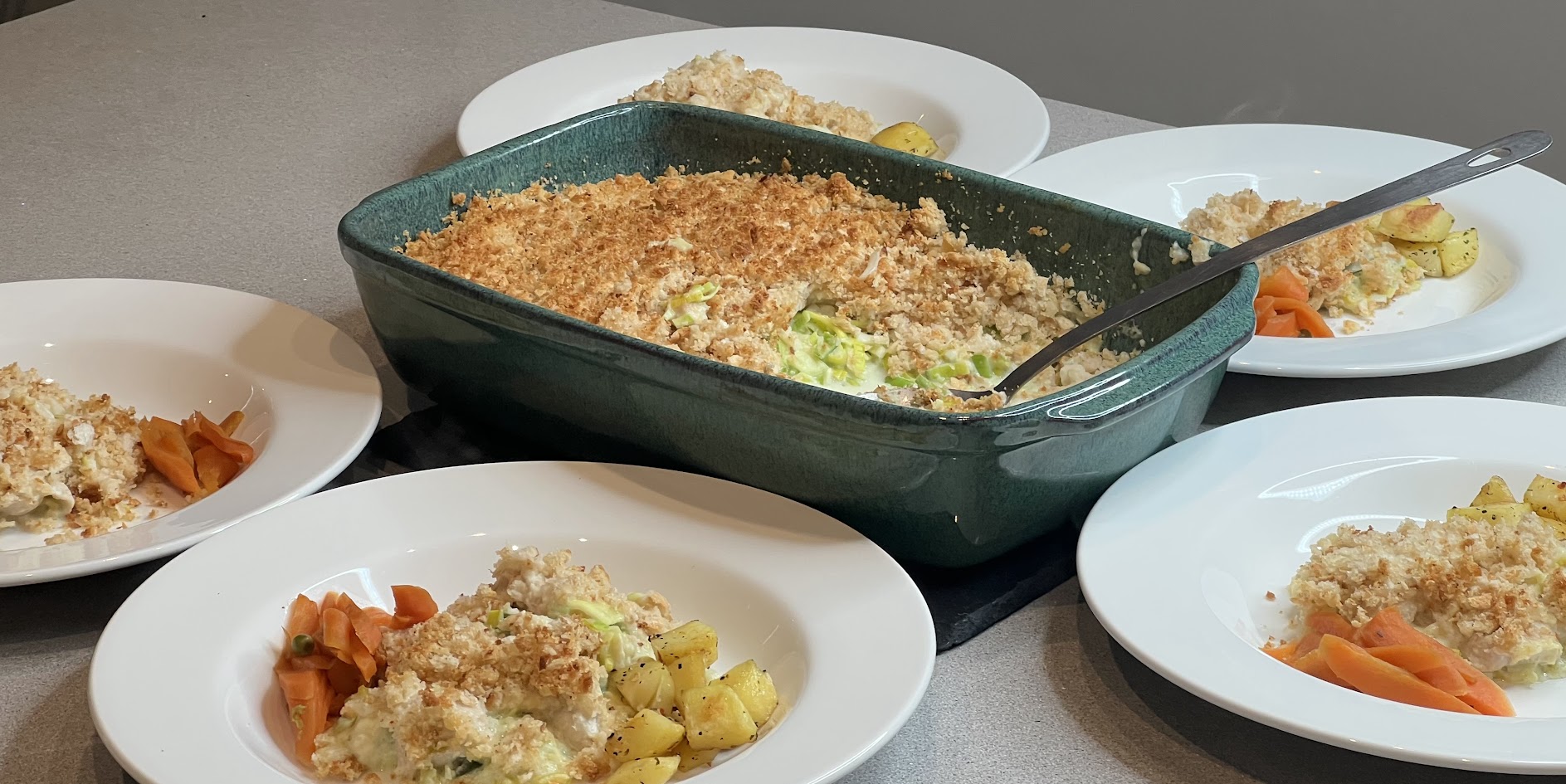 Chicken and leek bake with golden breadcrumbs in a sharing dish, served with roast potatoes and carrots by Noba Kitchen.