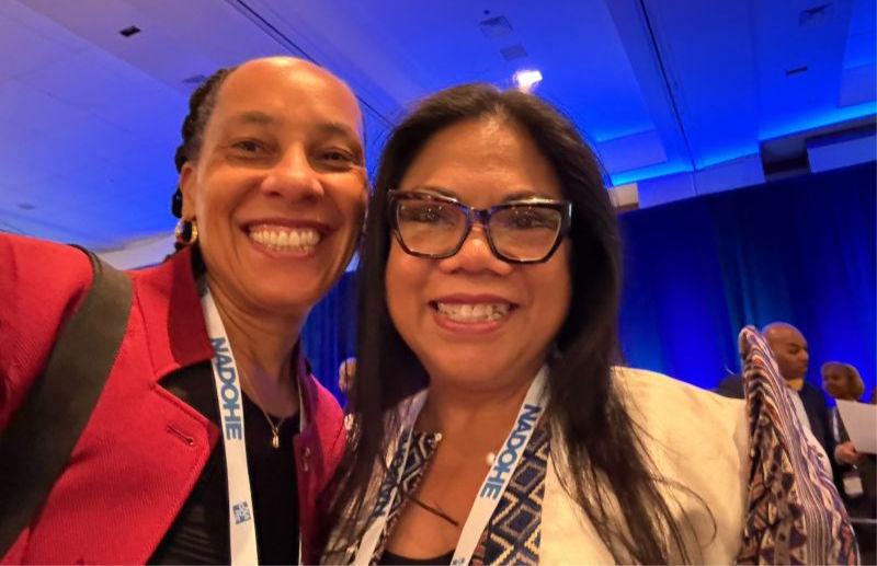 Chinyere Oparah and Emelyn Dela Peña smile into the camera wearing conference tags,