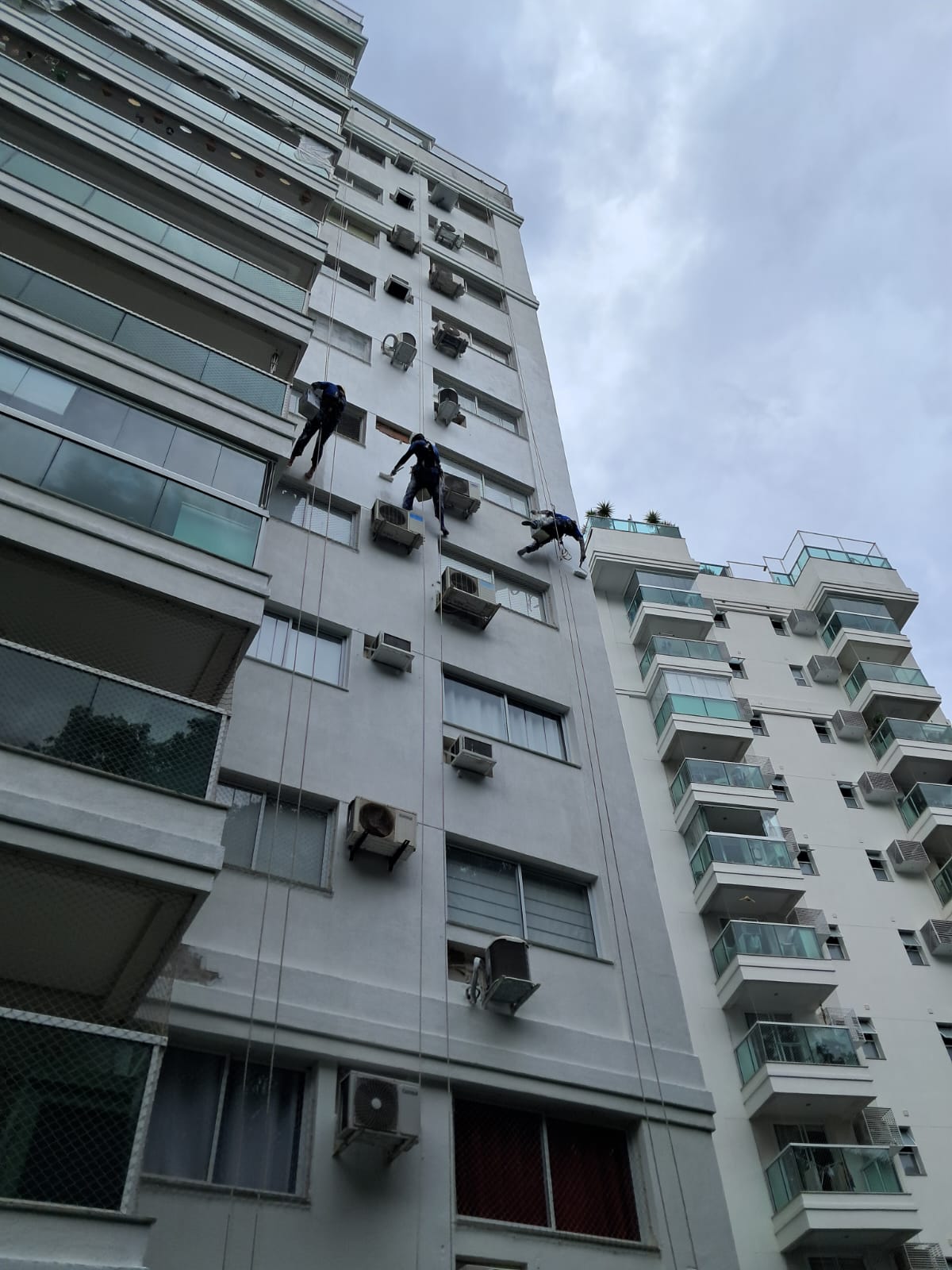 Profissionais em trabalho em altura durante manutenção de fachada predial