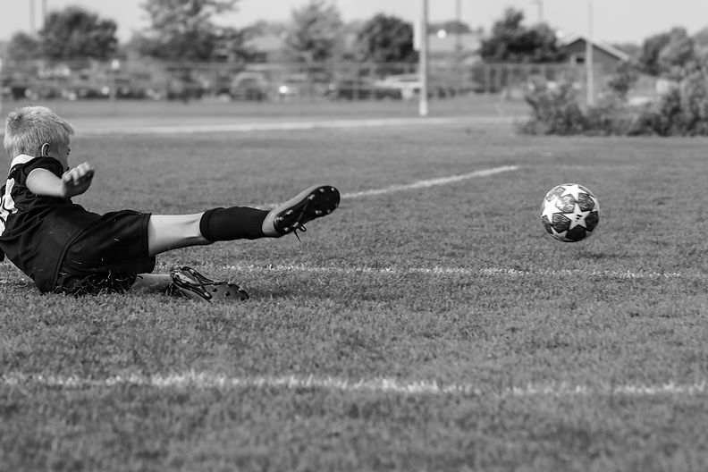 RFA player sliding to kick soccer ball