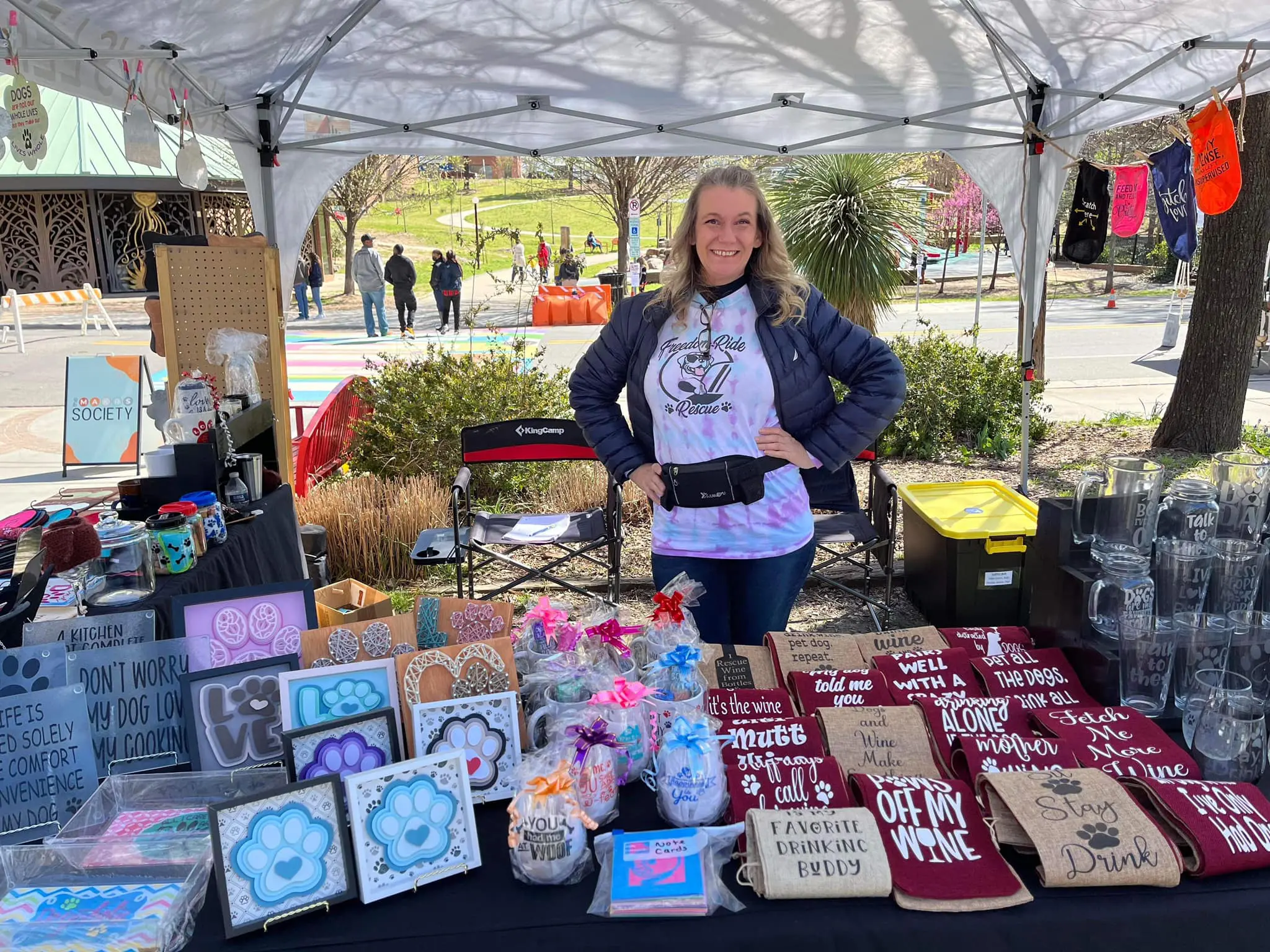 Freedom Ride Rescue Volunteer standing behind booth with products.