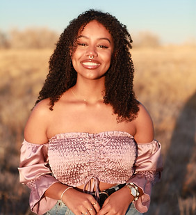 Meron standing in a field smiling at the camera