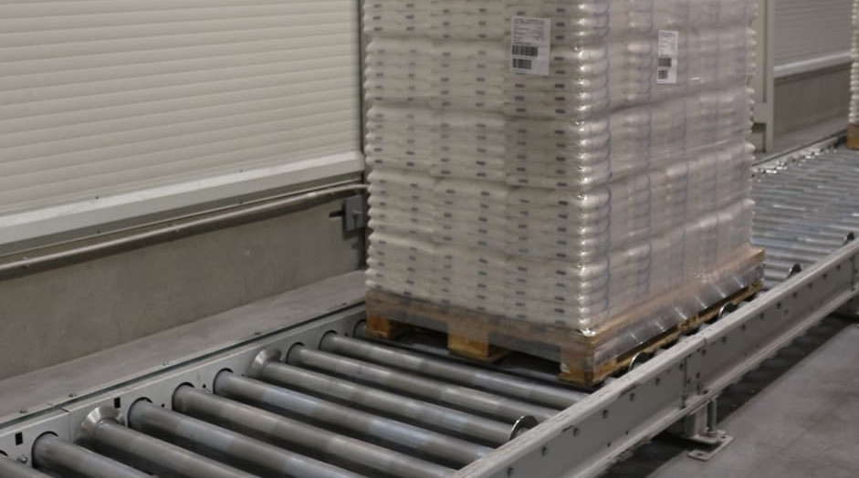 Roller conveyor for transporting and accumulating pallets of packaged goods