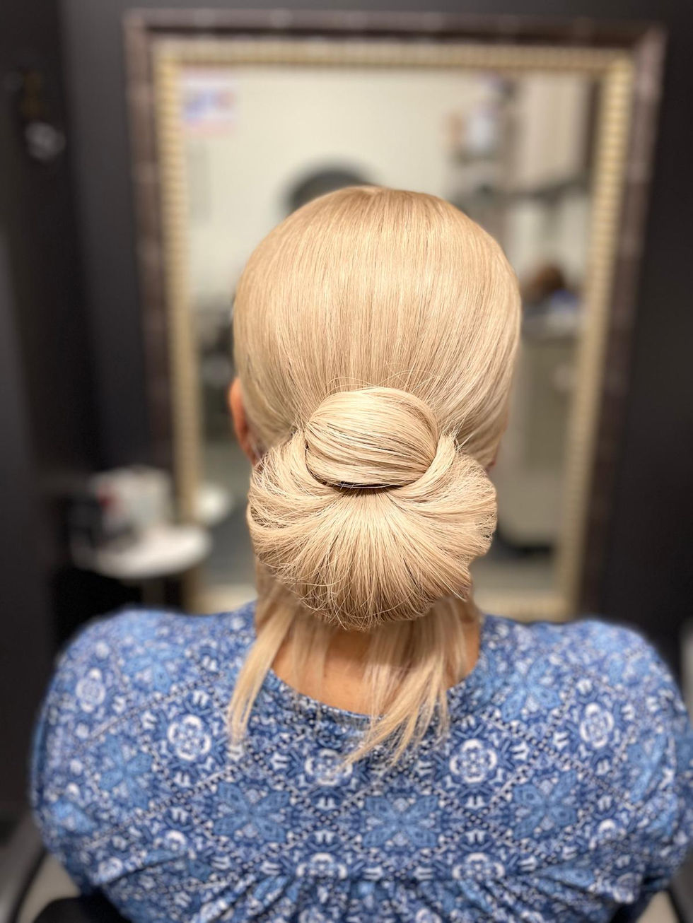 Elegant blonde low bun with round shape and delicate hair strands.