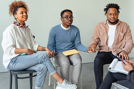 three polyamorous partners sitting on chairs in a group counselling session