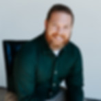 Rick Mullenix in green shirt leaning forward sitting on a chair.