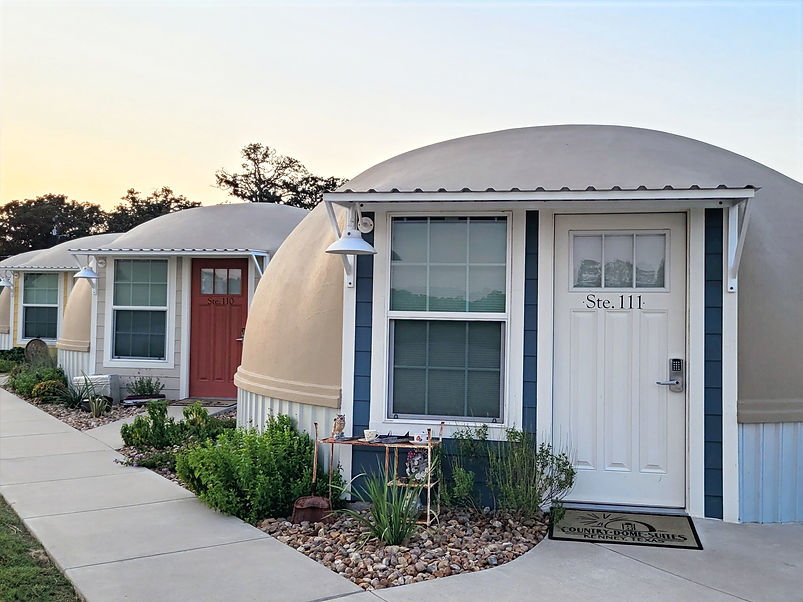 Exterior of dome suite Ste. 111 with covered entry, keyless entry lock, and landscaped walkway at Country Dome Suites in Kenney, Texas