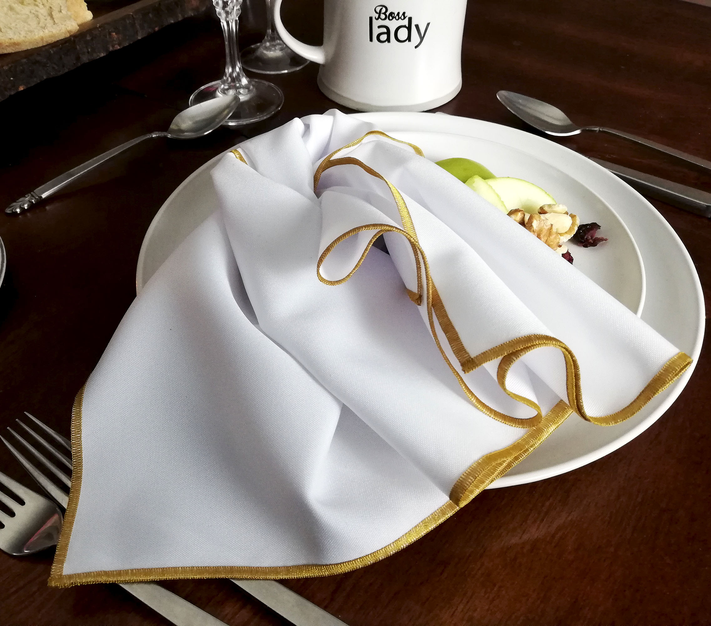 White napkin with gold trim on a plate with apples