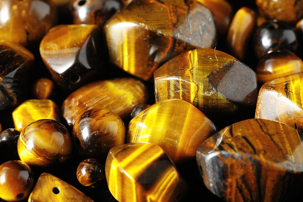 A close-up view of polished tiger's eye stones, showcasing their rich golden-brown hues and distinctive, swirling patterns.