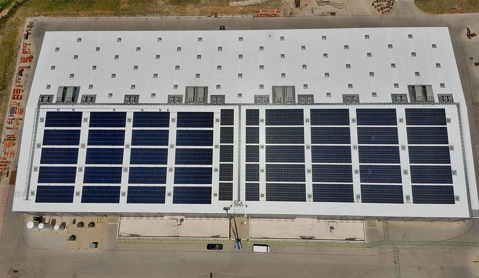 Aerial view of a large industrial facility showcasing rows of solar panels installed on its roof, highlighting a commitment to sustainable energy solutions.