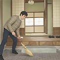古民家を箒で清掃する男性