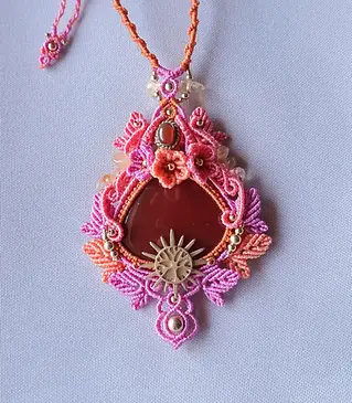 Talisman personnalisé en micromacramé avec cornaline, élément soleil doré, fleurs et feuilles tissées dans des tons rose, orange et saumon.