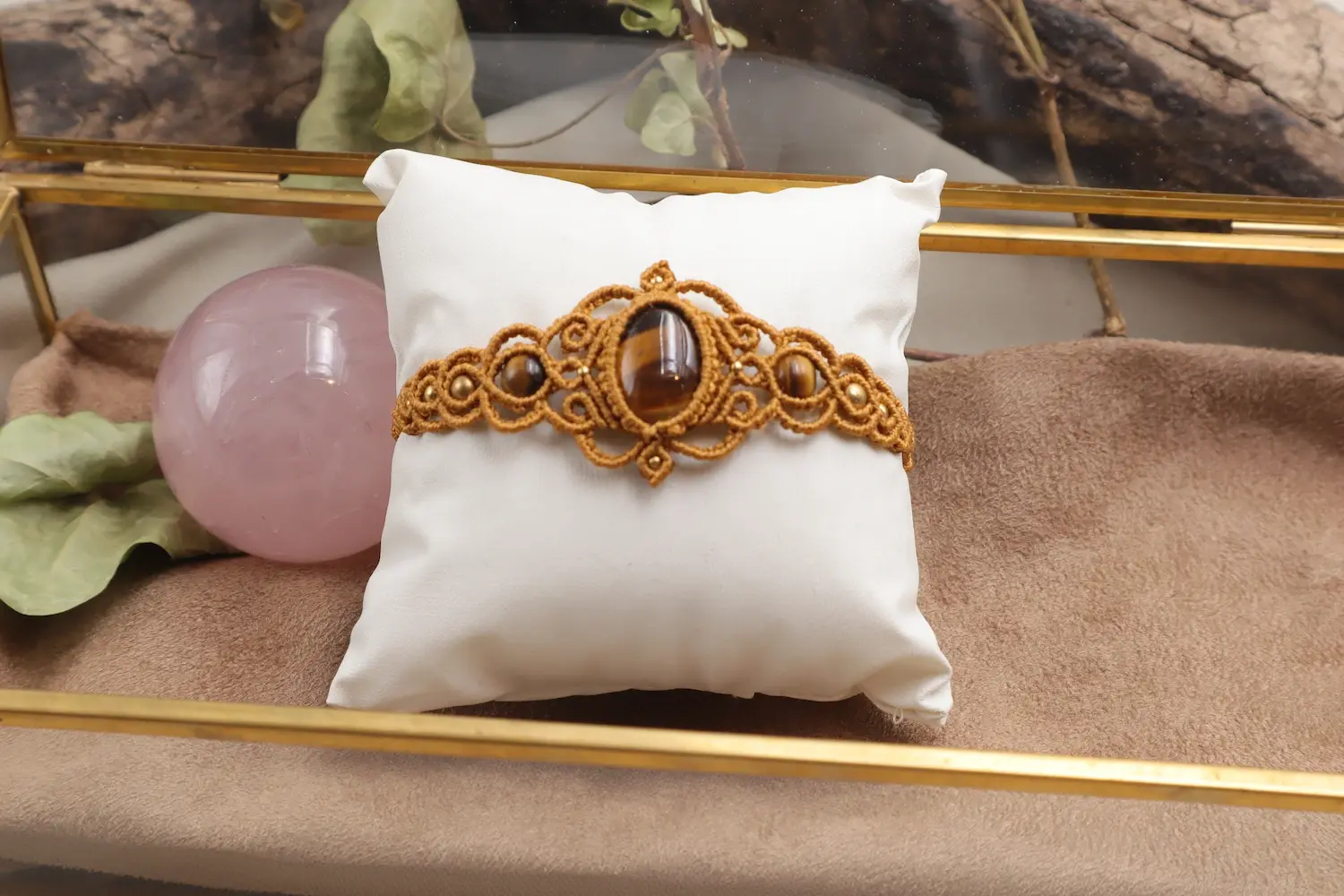 Bracelet macramé doré Œil de tigre Arabesque présenté de face sur coussin blanc