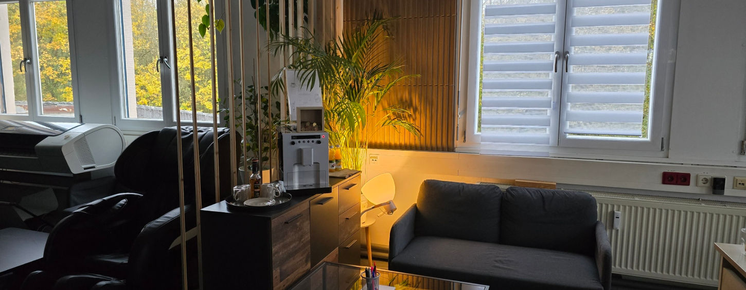 Modern eingerichtetes Büro mit PCs, einem Farbfächer auf dem Tisch und einem Fernseher zur Anzeige aktueller Projekte, ideal für kreative Arbeitsumgebungen, Kundenberatung und effiziente Projektabwicklung.