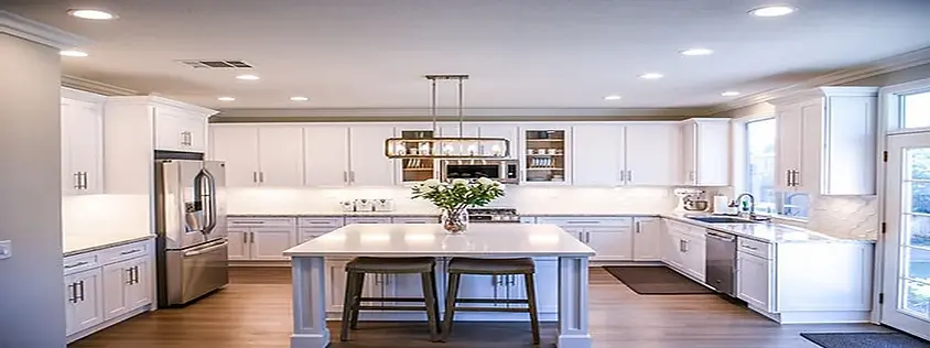 Bright, modern white kitchen with island, stainless steel appliances, and fresh flowers—Neat Nathalie & Co. home organization result