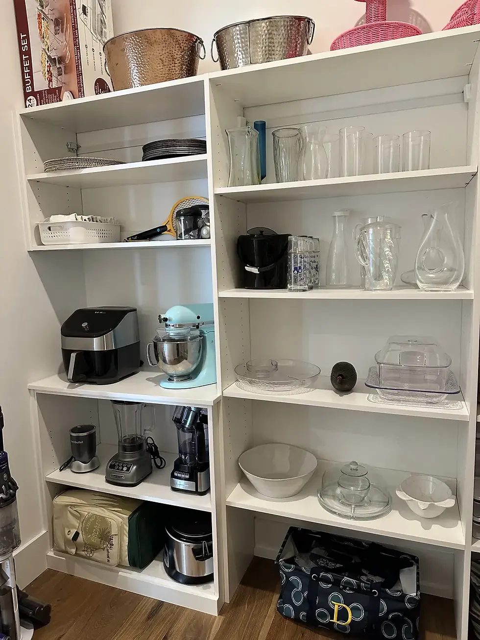 Spacious white pantry with small kitchen appliances, glass jars, and elegant entertaining pieces nea