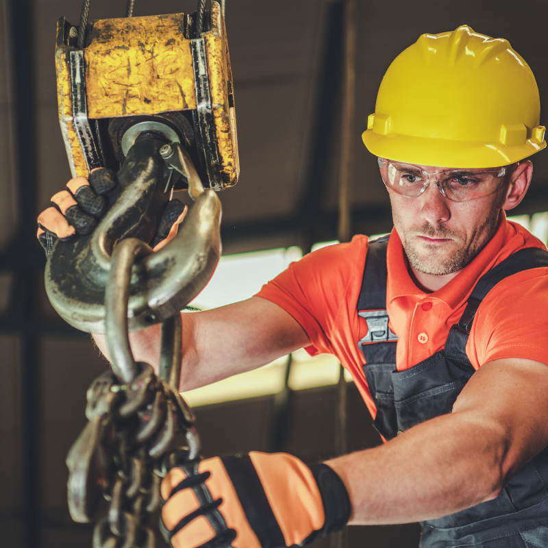 Construction worker using lifting equipment on site