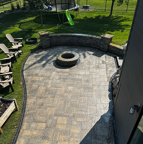 A hardscaped patio with a seat wall and fire pit.