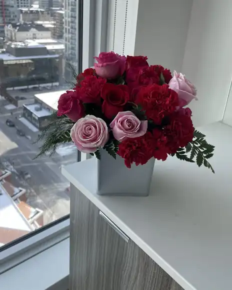 Red and pink roses and carnations by a window