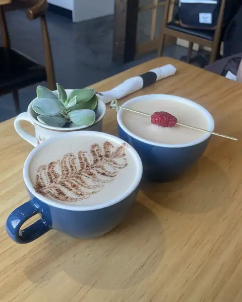 A latte and a raspberry drink on a wooden cafe table