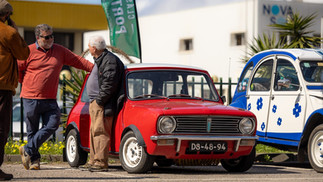 Famílias e entusiastas reunidos junto a automóveis clássicos no parque, celebrando o Dia da Mulher em ambiente festivo