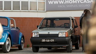 Famílias e entusiastas reunidos junto a automóveis clássicos no parque, celebrando o Dia da Mulher em ambiente festivo