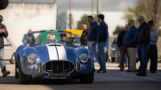 Famílias e entusiastas reunidos junto a automóveis clássicos no parque, celebrando o Dia da Mulher em ambiente festivo
