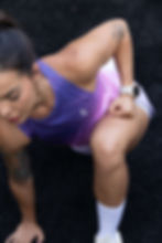 Mujer fitness en posición de entrenamiento funcional usando top deportivo transpirable