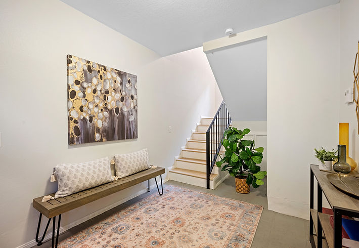 Entryway with bench, artwork, stairs, and decorative rug, featuring a welcoming aesthetic.
