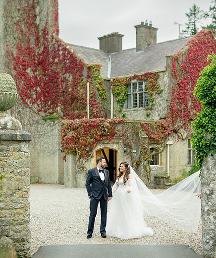 A bride and groom smiling in front of a castle in Ireland