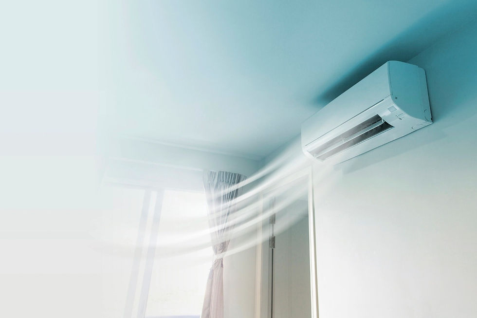 Indoor wall mounted air conditioner blowing cool air into a bright room with a window and curtain visible.