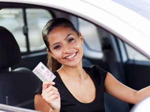 Young woman inside a car holding her new driver’s licence