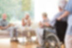 Seniors socializing and enjoying refreshments together in a retirement home lounge.