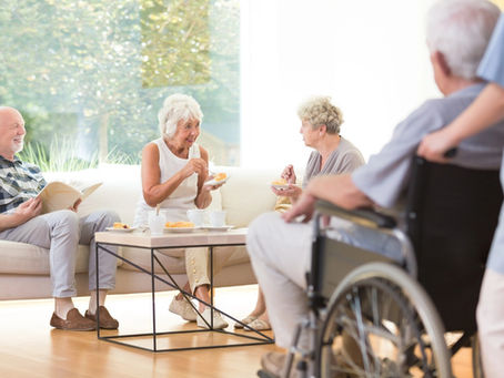 Seniors socializing and enjoying refreshments together in a retirement home lounge.