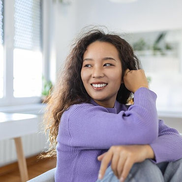 happy-asian-woman-sitting-sofa-home-looking-camera-portrait-comfortable-woman-winter-cloth