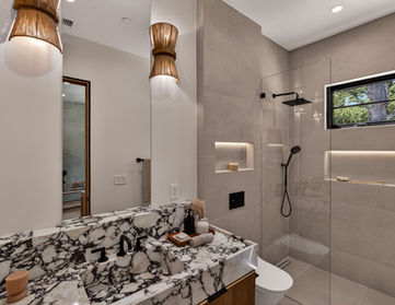 Luxury bathroom in Woodland Hills Los Angeles with Calacatta Viola marble vanity, glass walk-in shower, black fixtures, and illuminated wall niches