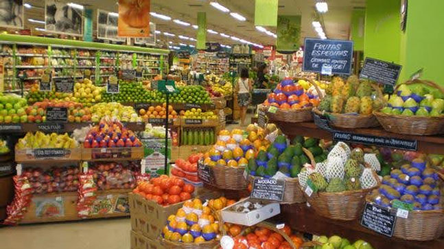 Brown baskets filled with green, orange, brown, yellow and red fruits with a green background. 