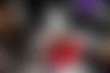 A person holds up plant material out of a red plastic container sitting on a table